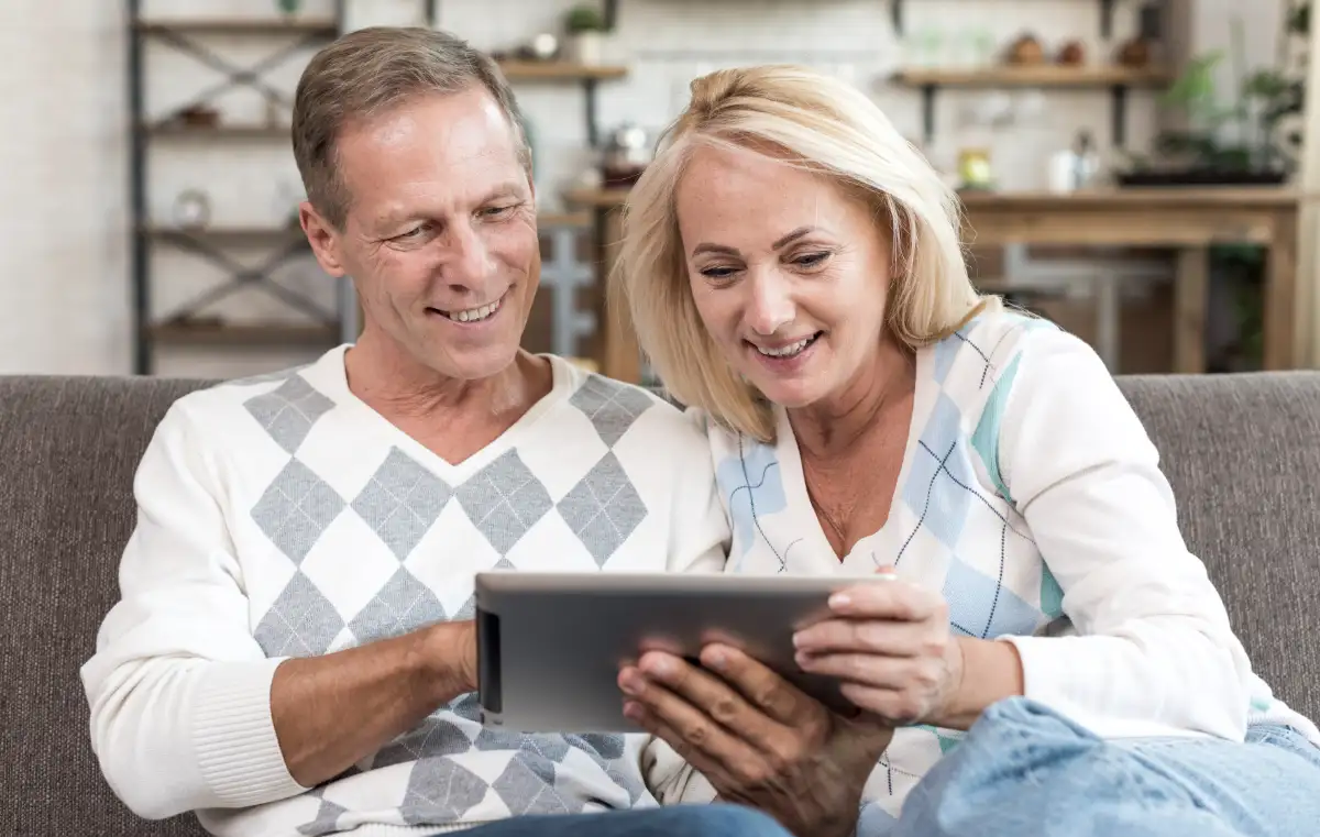 happy retired couple holding tablet reviewing tips to pay off your mortgage faster